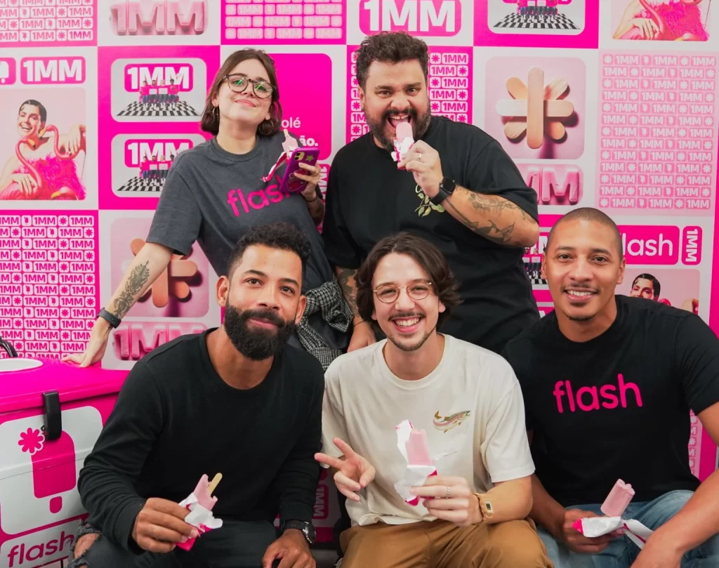 Equipe da empresa Flash saboreando picolés personalizados durante evento corporativo com marketing de experiência
