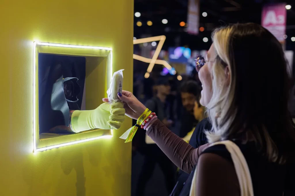 Mulher alegre recebendo sorvete de brinde corporativo em ação interativa com parede surpresa